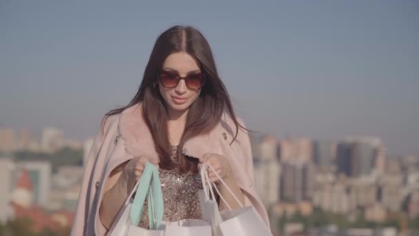 Mujer adicta a las compras sorprendida mirando en bolsa de compras al aire libre — Vídeos de Stock