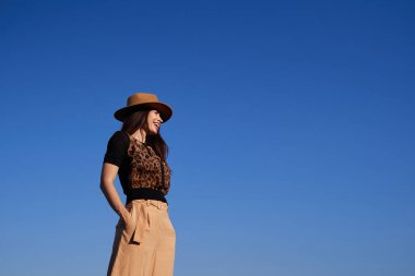 Stylish girl wearing hat on sky background with copy space