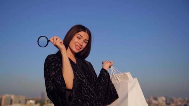 Chica glamour feliz con lupa y bolsas de compras — Vídeos de Stock