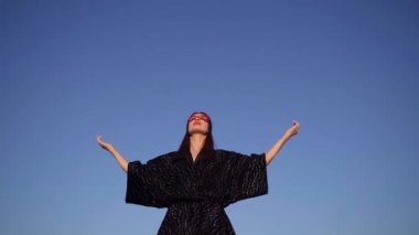 Supergirl in mask looking up with spreading hands praying