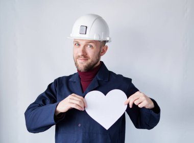 Contractor or engineer in hard hat with white paper heart