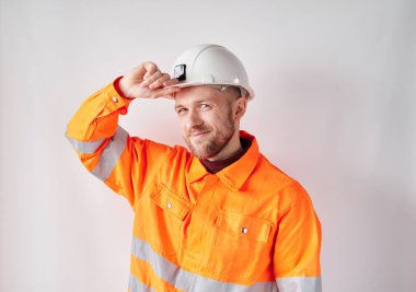 Building contractor in orange vest correcting hardhat