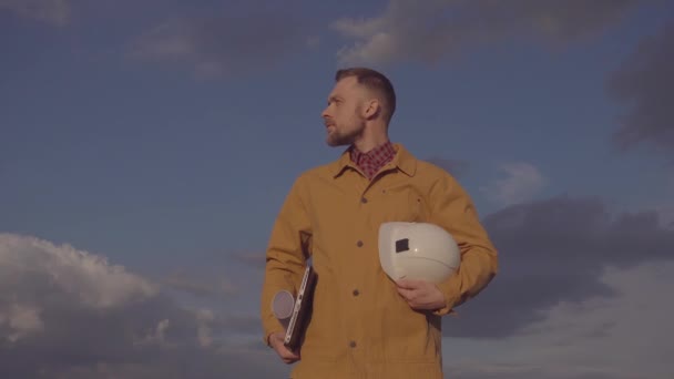 Construction industry worker holds helmet, plans and laptop — Wideo stockowe