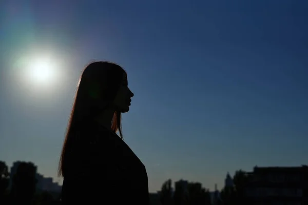 Długie włosy kobieta sylwetka w słoneczny dzień przed błękitnym niebem — Zdjęcie stockowe