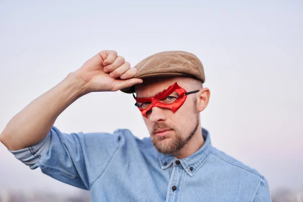 Superheldenmännchen in roter Maske und Mütze beim Stadtanblick bei Sonnenuntergang — Stockfoto