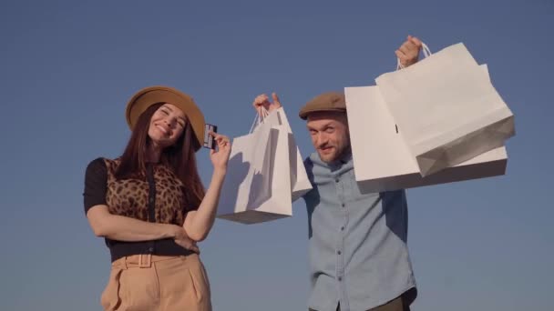 Bonito casal jovem elegante com cartão de crédito e sacos de compras — Vídeo de Stock