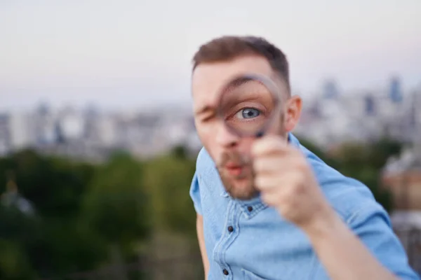 Closeup man looking through magnifying glass outdoor — Stock Photo, Image