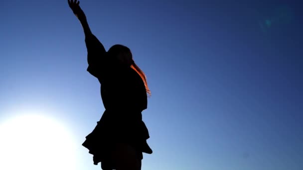 Χαριτωμένο μακριά μαλλιά κορίτσι σιλουέτα χορεύουν ενάντια στον ουρανό στο ηλιοβασίλεμα — Αρχείο Βίντεο