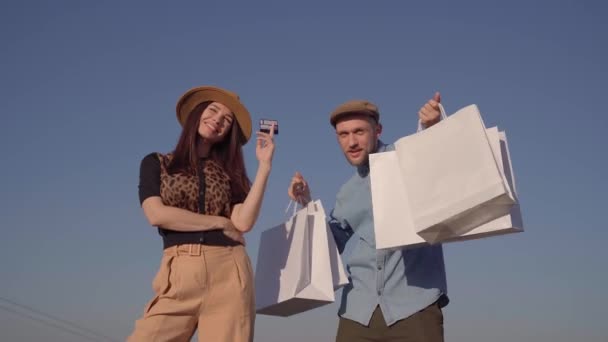 Elegante casal hipster feliz com cartão de crédito e sacos de compras — Vídeo de Stock