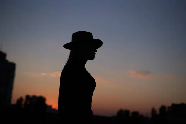 Silueta módní dlouhé vlasy žena v klobouku při západu slunce — Stock fotografie