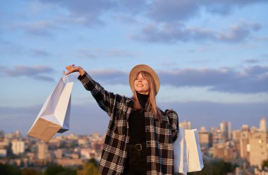 Alışveriş konsepti: açık havada beyaz çantalı şapkalı neşeli kız