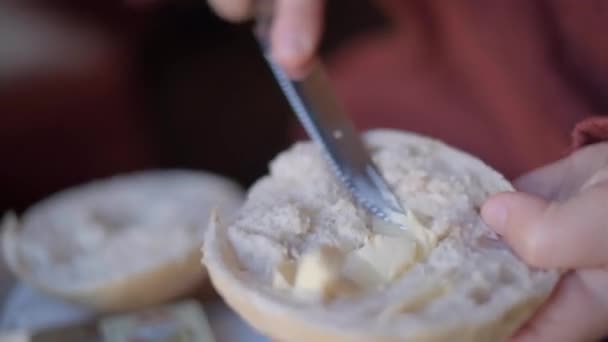 Frukostkoncept: kvinna sprider smör på bulle med kniv, 4k — Stockvideo
