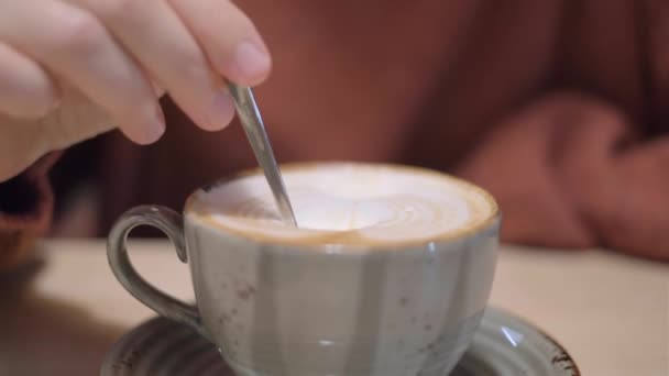 한 여성 이 카페에 있는 큰 컵에 크림 라떼 커피를 흔들며 4k — 비디오