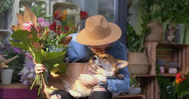 笑顔ヒップスター男性は 新鮮な春のデイジーの花の花束とウェルシュコーギー犬とサングラスと帽子を身に着けています 母の日 バレンタインデーまたは国際女性デーの概念 4Kビデオ映像 — ストック動画
