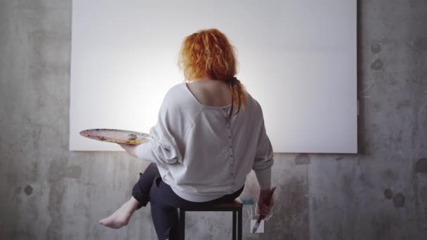 Female Painter Sitting Front White Canvas Holding Paintbrushes Palette Caucasian — ストック動画