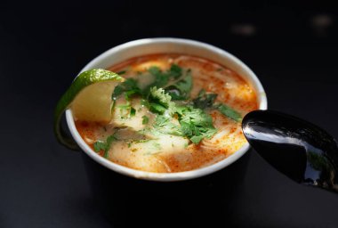 Tayland ya da Vietnam mutfağı: Tom Yum Goong baharatlı ve ekşi çorba ve siyah arka planda erişte. Kaşık ve kase ile erişte çorbası ve deniz ürünleri. Yüksek kaliteli resim 