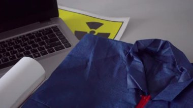 Siyah gaz maskesi, yuvarlanmış planlar ve dizüstü bilgisayar. Arka planda radyasyon işareti olan mühendisler masasında. Radyoaktif, nükleer yapı veya atom mühendisliği konsepti. 4k video kaydı