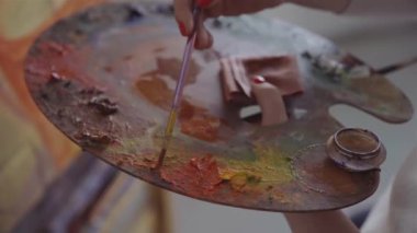 Artist mixes paints on the palette before painting a picture, painter at the studio, creator makes piece of art. Painting tools for art hobby. High quality 4k footage