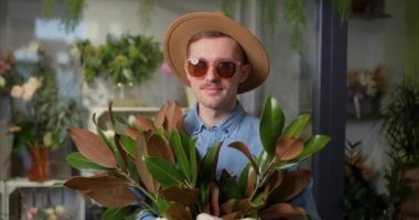 Mothers Day, Valentines Day or International Womens Day concept. Smiling hipster male person in sunglasses and hat with fresh spring flower bouquet and welsh corgi dog. High quality 4k video