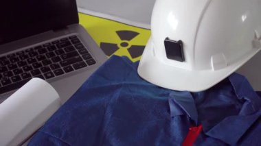 Radyoaktif, nükleer yapı veya atom mühendisliği konsepti. Erkek, eldivenleri yuvarlanmış planlar, beyaz şapka ve dizüstü bilgisayarla birlikte masanın üzerine koyuyor.