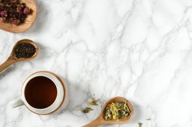 Bir fincan çay ve çay, ahşap kaşıklar ve tabaklar içinde.