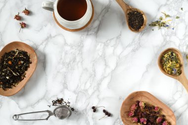 Bir fincan çay ve çay, ahşap kaşıklar ve tabaklar içinde.