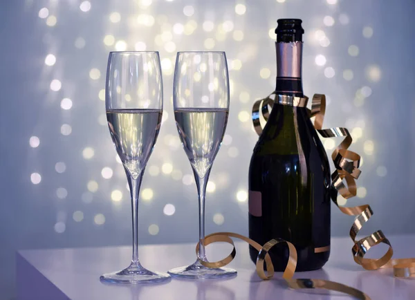 Tho Glas Champagne Och Flaska Mot Suddiga Ljus Bakgrund — Stockfoto