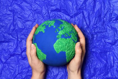 Mavi kağıt arka planda el yapımı Dünya modeli olan eller