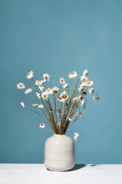 Mavi bir duvarın karşısında güzel kuru çiçekler.