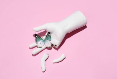 Plaster broken hand with butterfy on a pink background