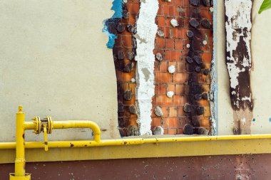 Binanın gaz borusunun bir kısmı bombardımandan sonra hasar görmüş. Yanmış bir cephe ve görünür bir tuğla duvar. Rusya 'nın Ukrayna' ya karşı savaşı.