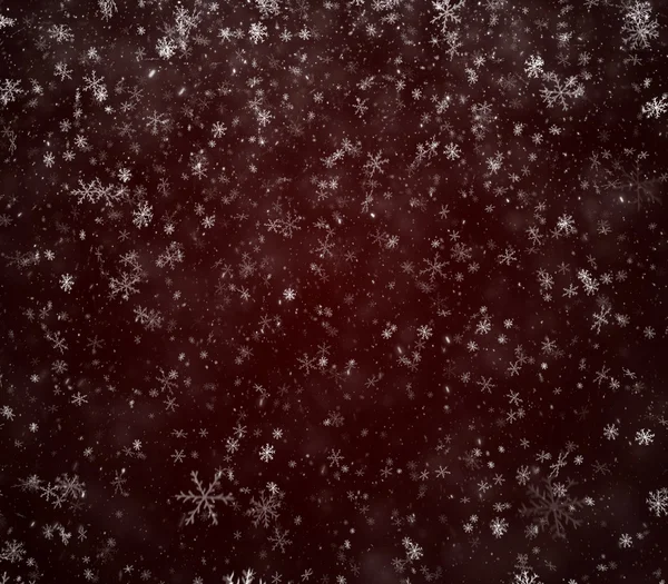 Flocons de neige tombant sur un fond rouge foncé — Photo