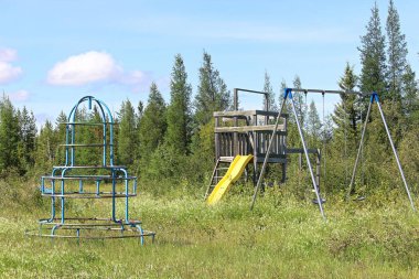 An unmaintained abandoned playground at a campsite clipart