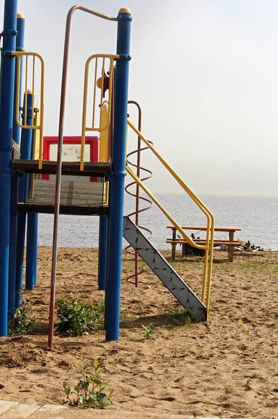 A playground slide beside a large lake — Stock Photo, Image