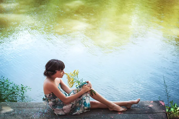 Girl sitting by a lake — Stock Photo, Image