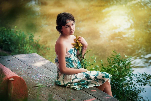 Dívka sedí u jezera — Stock fotografie