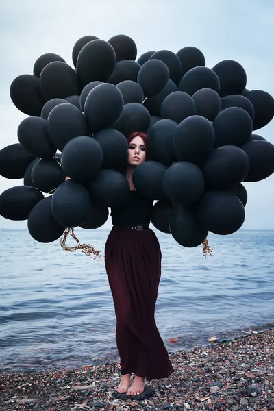Beautiful girl walking with black balloons — Stock Photo, Image