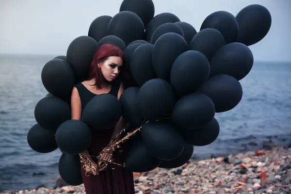 Beautiful girl walking with black balloons — Stock Photo, Image