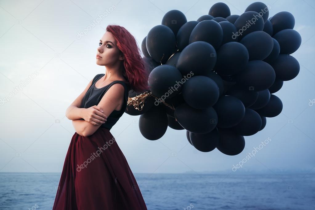 Beautiful girl walking with black balloons