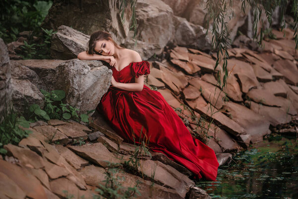 Romantic portrait of beautiful woman in red dress in the garden full of roses.