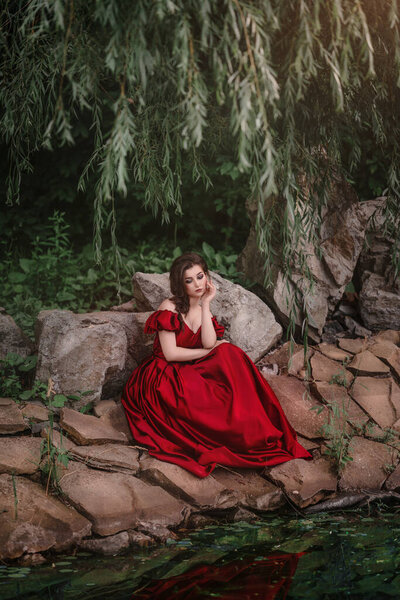Romantic portrait of beautiful woman in red dress in the garden full of roses.