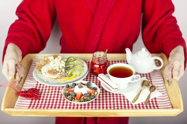 Un uomo vestito con un vassoio porta la colazione per il suo amato Immagine Stock