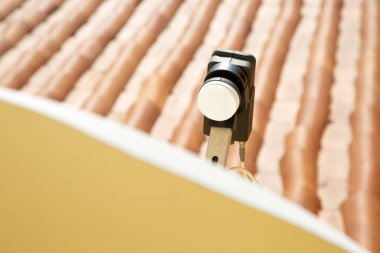 Black parabolic antenna transmitter with tiled roof in background. Internet and tv supply. Connection. High tech device in historic center. 