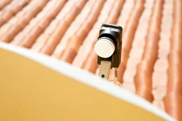 Black parabolic antenna transmitter with tiled roof in background. Internet and tv supply. Connection. High tech device in historic center. 