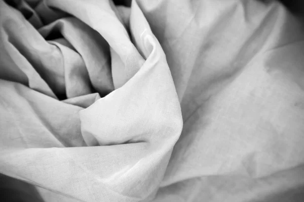 Black and white background picture of crumpled fabric. Cotton textile sample. 100 percent viscose natural material. Copy space. Sowing concept. Chaotic artistic wallpaper. Morning bed sheet. 