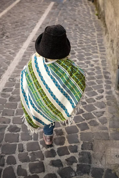 Pançolu bir bebek ve kaldırımda yürürken şapkasını hissetti. Arkadan bak, yüz yok. Bebek modası, Latin stili. Renkli çizgili püsküllü pelerin. Bağımsızlık kavramı