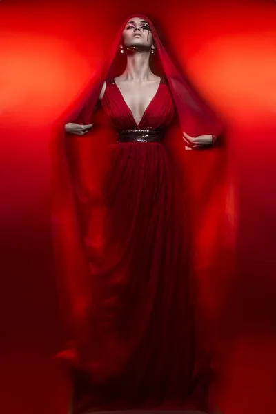 Красивая горячая брюнетка в красном платье на красном портрете — стоковое фото
