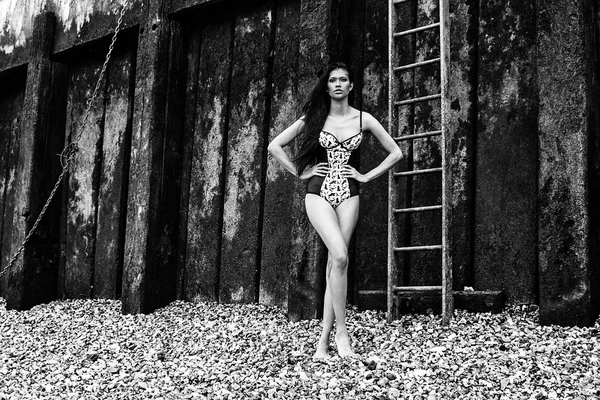 Lingerie bikini young sexy latin american photo model posing on a beach next to an old muddy wall — Stock Photo, Image