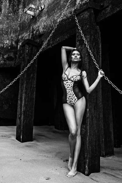 Bikini de lencería joven sexy modelo de fotos latinoamericanas posando en una playa junto a una vieja pared fangosa — Foto de Stock