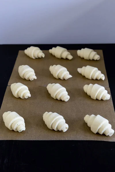 Croissants Utworzone Surowego Ciasta Leżą Rzędach Papierze Pieczenia Przed Wysłaniem — Zdjęcie stockowe